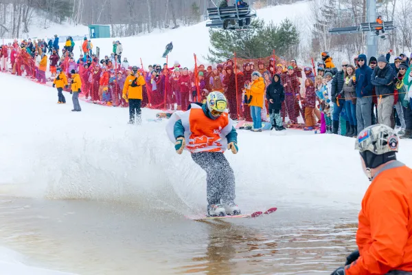 A man in spring ski gear pond skims on snow. 