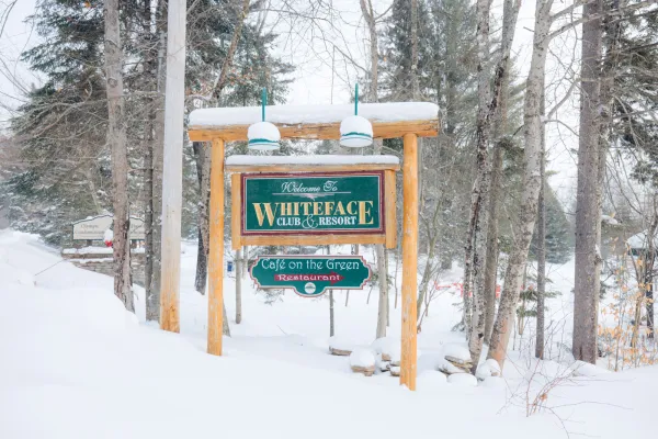 Roadside sign for Whiteface Club & Resort covered in snow