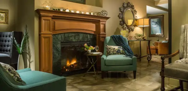 The luxurious women's lounge decorated with a robust fireplace, comfortable chairs, and candle light.