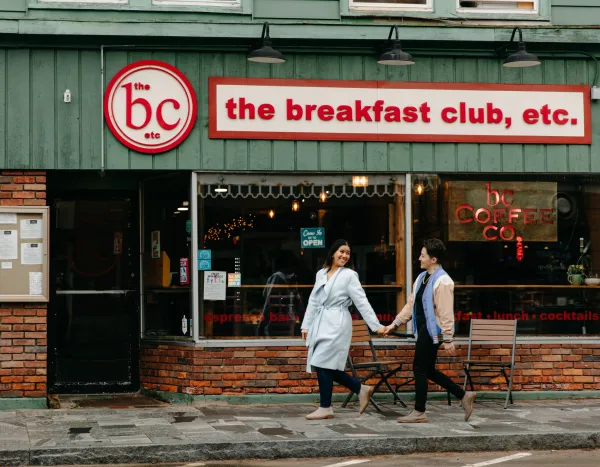 Two women smile and walk to a breakfast spot.