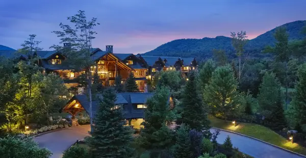 illuminated lodge at sunset with mountains.