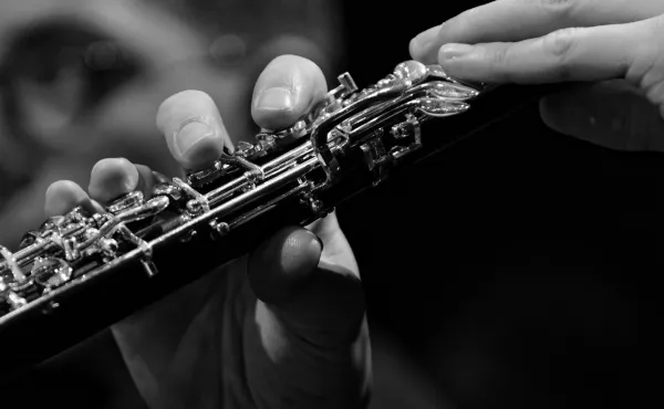 Black and white stock image of a person's hands holding an oboe