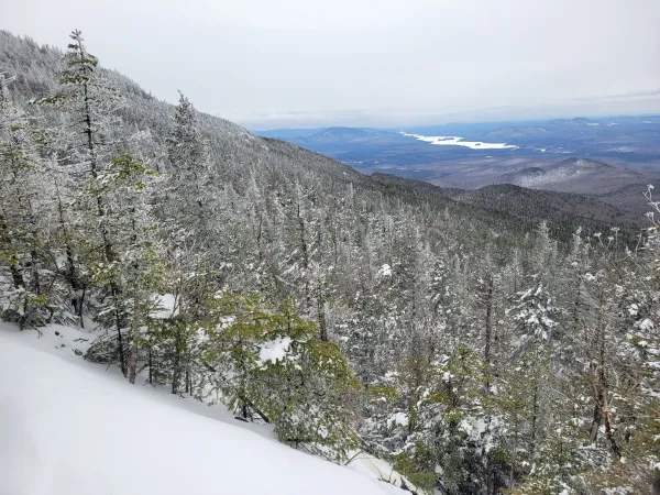 A snowy view down towards a long lake