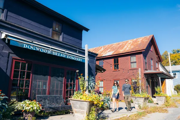 A man and woman walk to a restaurant on a sunny day. 