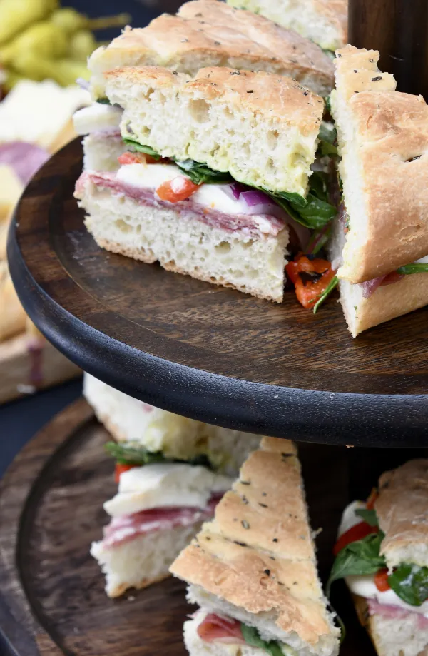 Tiered dark wooden platter with small sandwich triangles