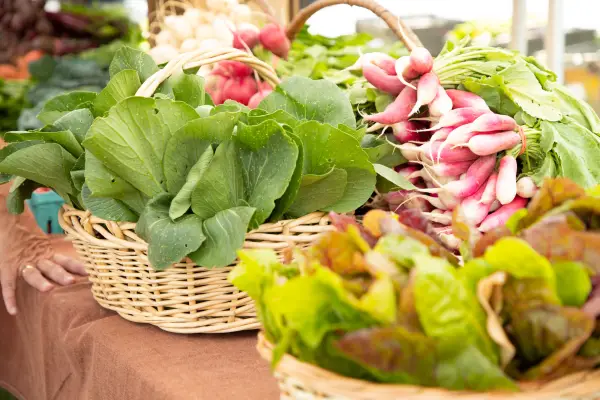 Baskets of greens and radishes on table at farmers' market