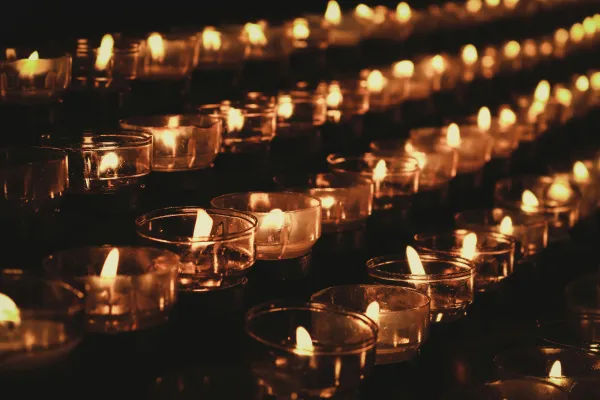 Rows of softly glowing tealight candles in clear holders.