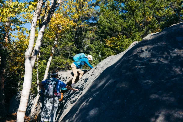 An older hiker going up a short rock face