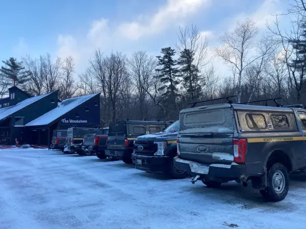 Line of NYS Forest Ranger trucks covered in frost lined up in parking lot of Mountaineer store in winter