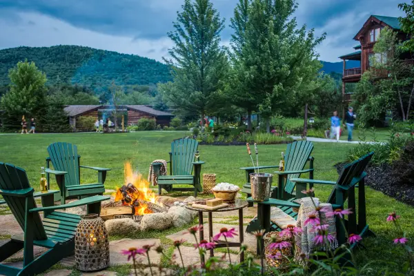 Adirondack chairs around an outdoor fire place.