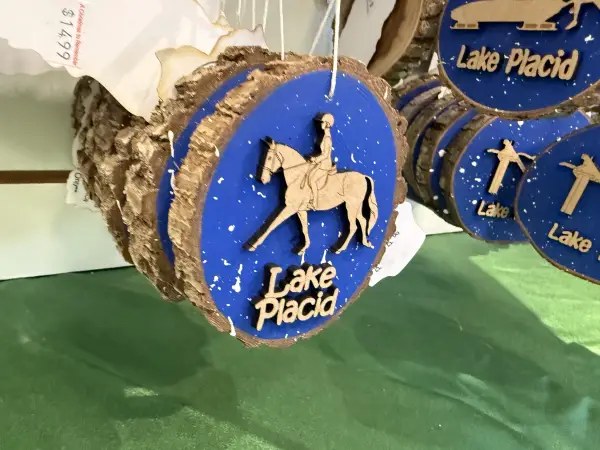 A lake placid themed log cookie ornament with a person riding a horse.