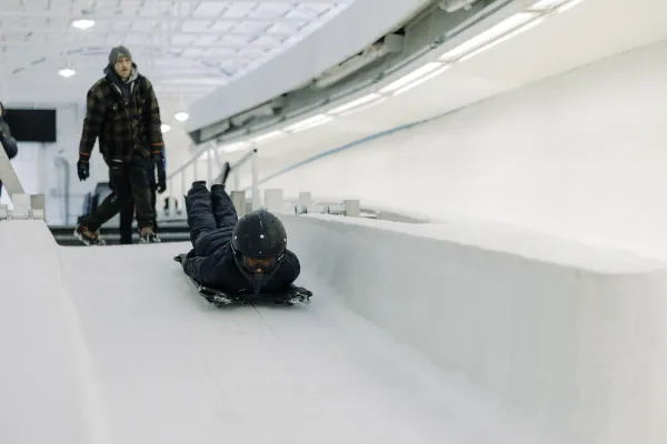 Person slides down ice track head first on skeleton sled