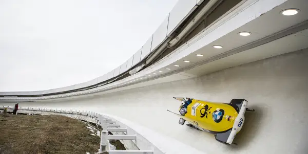A team of two in a yellow German bobsled glides down the Lake Placid track