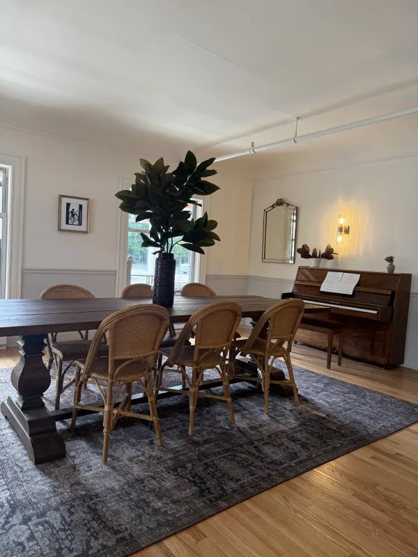 A large table with seating for 6 and a wooden piano in the background.