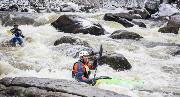 A man kayaks in white water. 