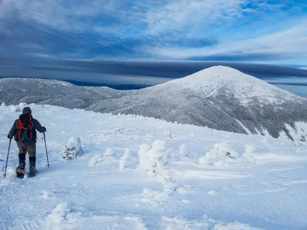 A snowshoer on a high alpine peak in the winter