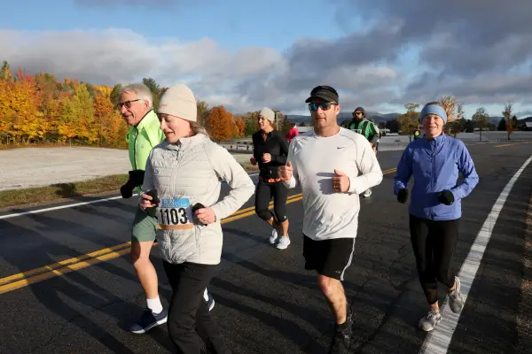 Group of runners on road with frosty fall foliage backdrop