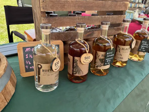 Gristmill's Black Fly bourbon and its delicious flavored variants displayed on a table at the Keene Valley Farmer's Market