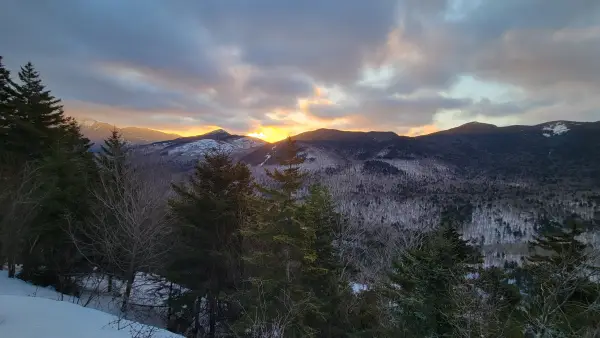 A sunrise view of snowy, evergreen-covered peaks