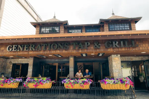 Senior couple sits at table on outdoor deck of restaurant with colorful flower boxes in front of them