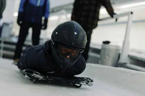 Person in helmet lays on skeleton sled on ice track