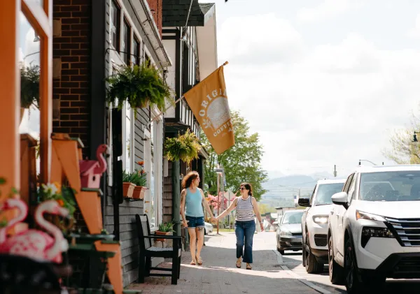Two women walk down a town road.
