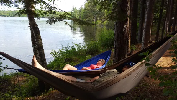 Two people in hammocks by the water
