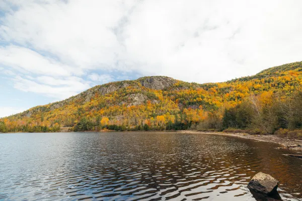 pond surrounded by rolling mountains with fall foliage