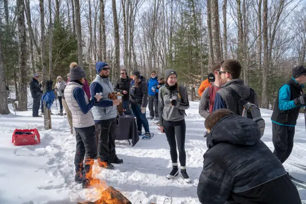 Cross-country skiers enjoying brews by a fire.