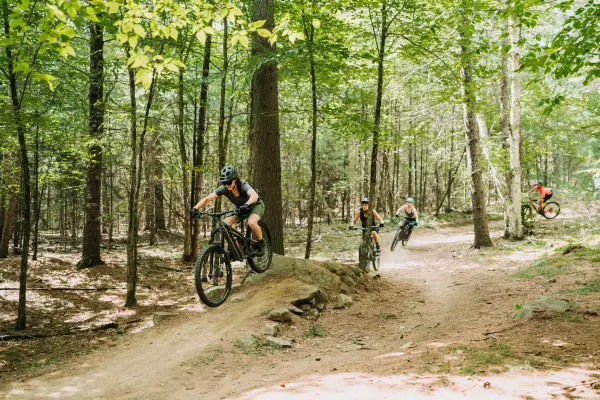 A bunch of people mountain biking over a ramp