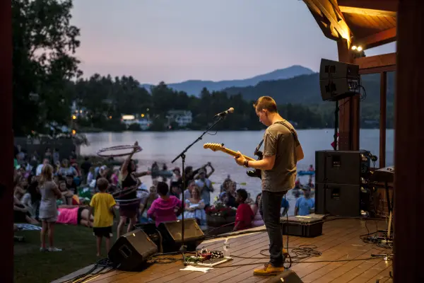 A guitarist performs in a bandshell for a crowd.