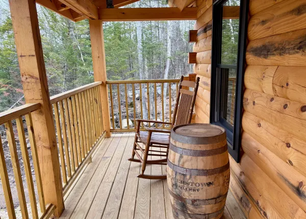 The covered porch with rocking chair and wine barrel table decor.