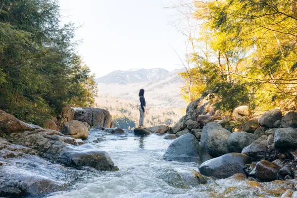 A woman stands on top of a waterfall