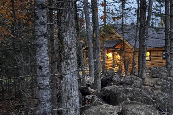 The warm glow of a log cabin through the trees.