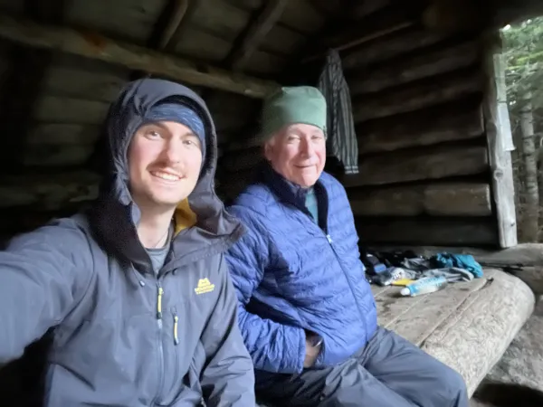 Smiling men sit in a lean to