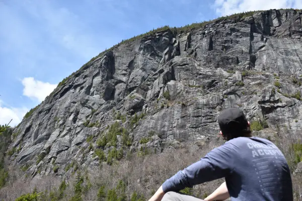 A hiker looking upo at a large rocky cliff