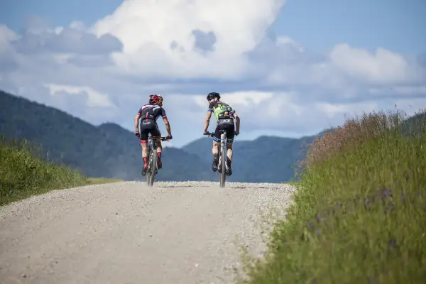 Two cyclists ride on a dirt road