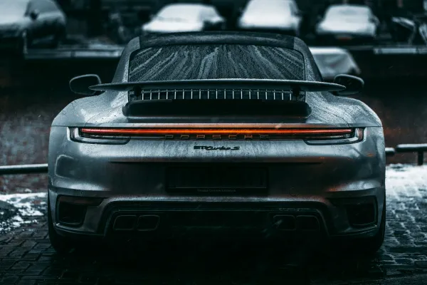 Stock image of the rear of a dark grey Porche sports car covered in water droplets interior space