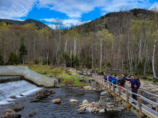 A bunch of hikers standing on a long, wooden bridge