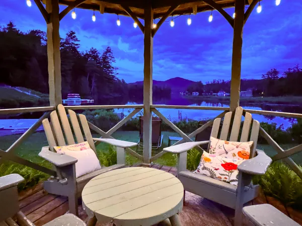 Adirondack chairs under the gazebo with string lights at dusk at Wildwood on the Lake.