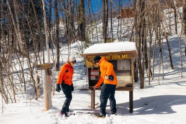 Two snowshoers signing into the Bear Den trail register