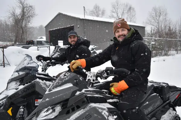 smiling faces atop polaris snowmachines