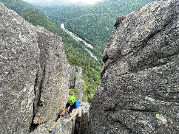 a rock climber ascends a crevice in the mountainside