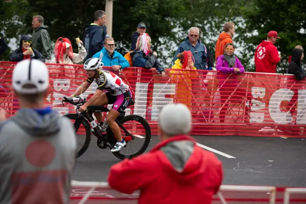 An athlete biking by a large crowd.