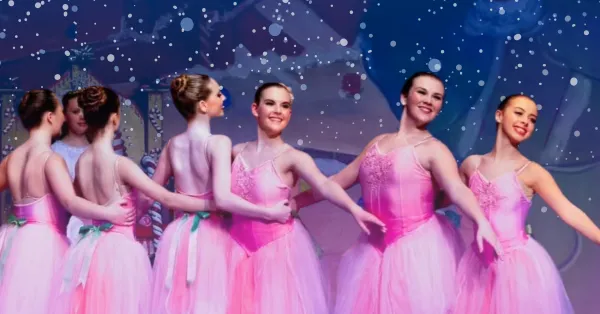 Group of young female ballerinas in pink dress costumes dance on stage with arms around one another