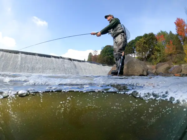 A man fishing under a dam