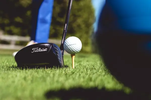 Golf ball on tee with driving club lined up on green grass