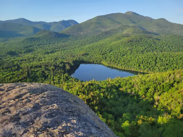 A small pond in front of tall mountains