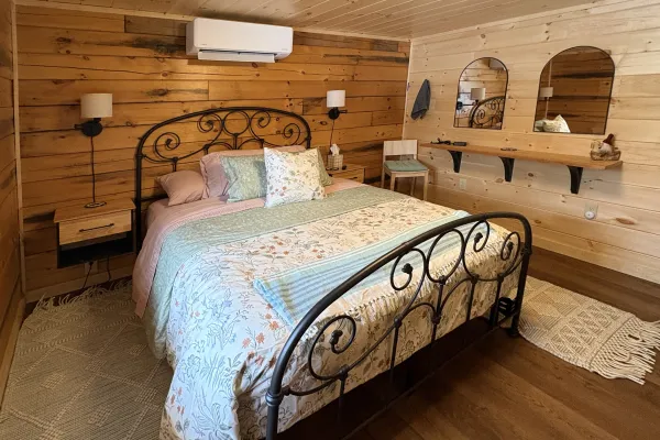 A black frame bed in a wood panel walled room.