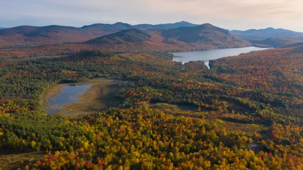 An aerial view of mountains and ponds aglow with fall colors